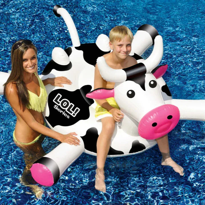 Enfant sur une bouée vache géante dans une piscine, ambiance estivale et détente aquatique.