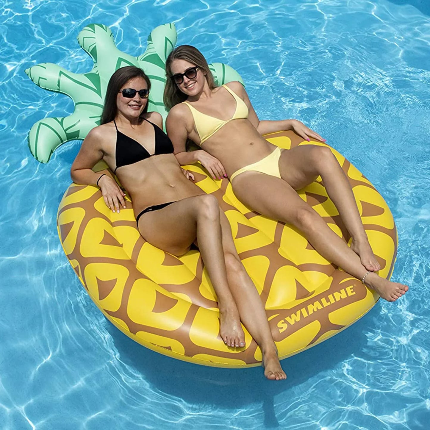Deux femmes sur un matelas gonflable ananas flottant dans une piscine bleue