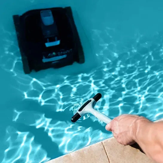 Nettoyage manuel et robotisé d'une piscine bleue avec balai et robot électrique