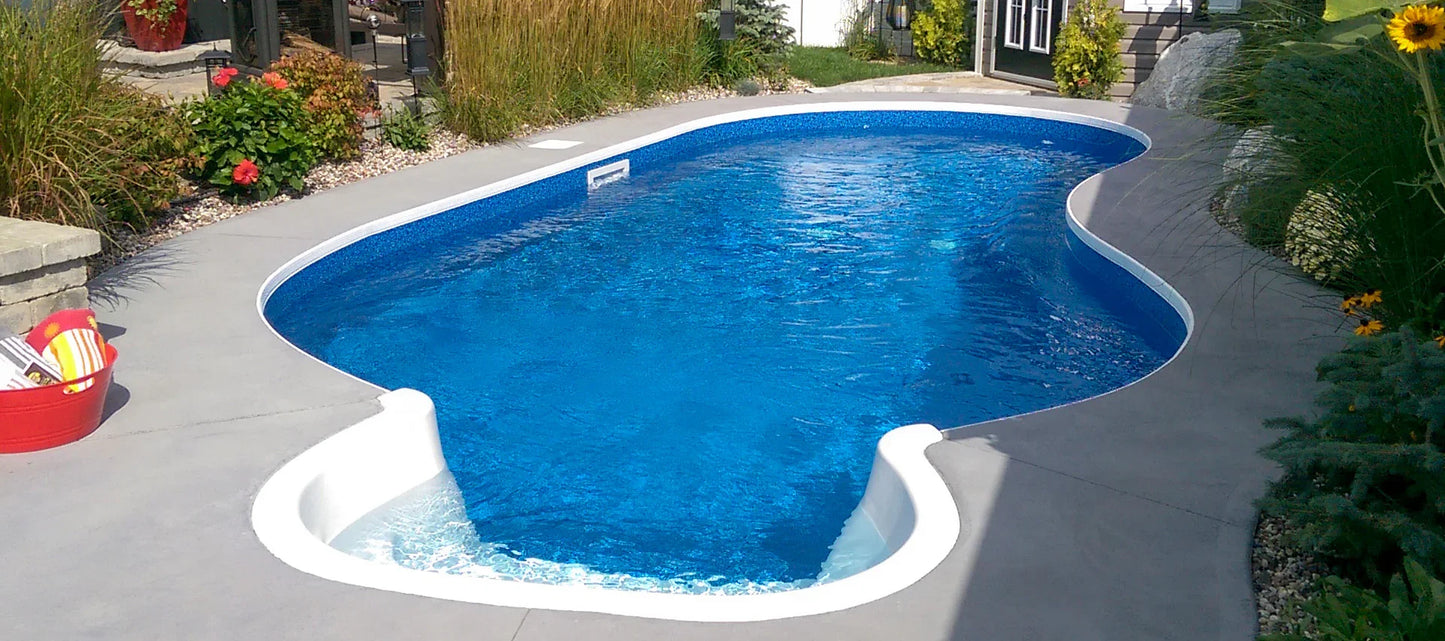 Piscine creusée bleue moderne entourée de végétation et terrasse en béton, idéale jardin.