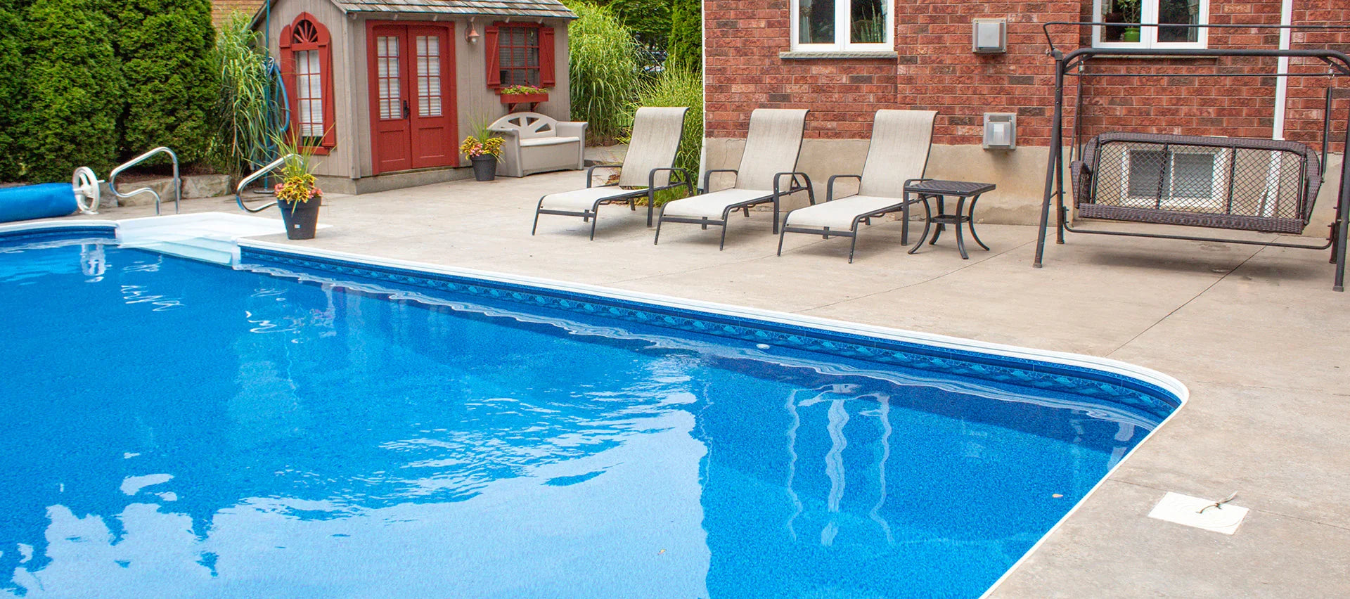 Piscine creusée extérieure avec eau bleue, terrasse, bains de soleil et chalet de jardin