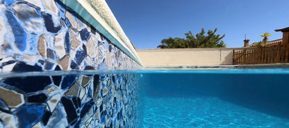 Piscine extérieure avec mosaïque bleue vue partiellement sous l’eau, ciel dégagé