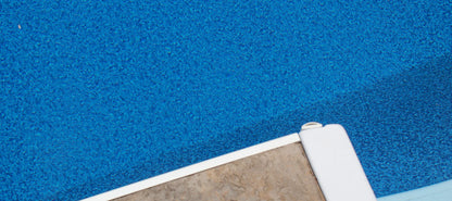 Angle d'une piscine avec margelle en pierre et liner bleu, vue rapprochée