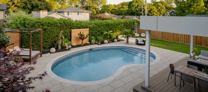 Piscine creusée moderne dans un jardin paysager avec terrasse, mobilier et végétation luxuriante