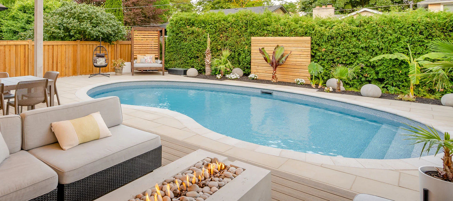 Piscine creusée moderne entourée de terrasse, mobilier extérieur et aménagement paysager.