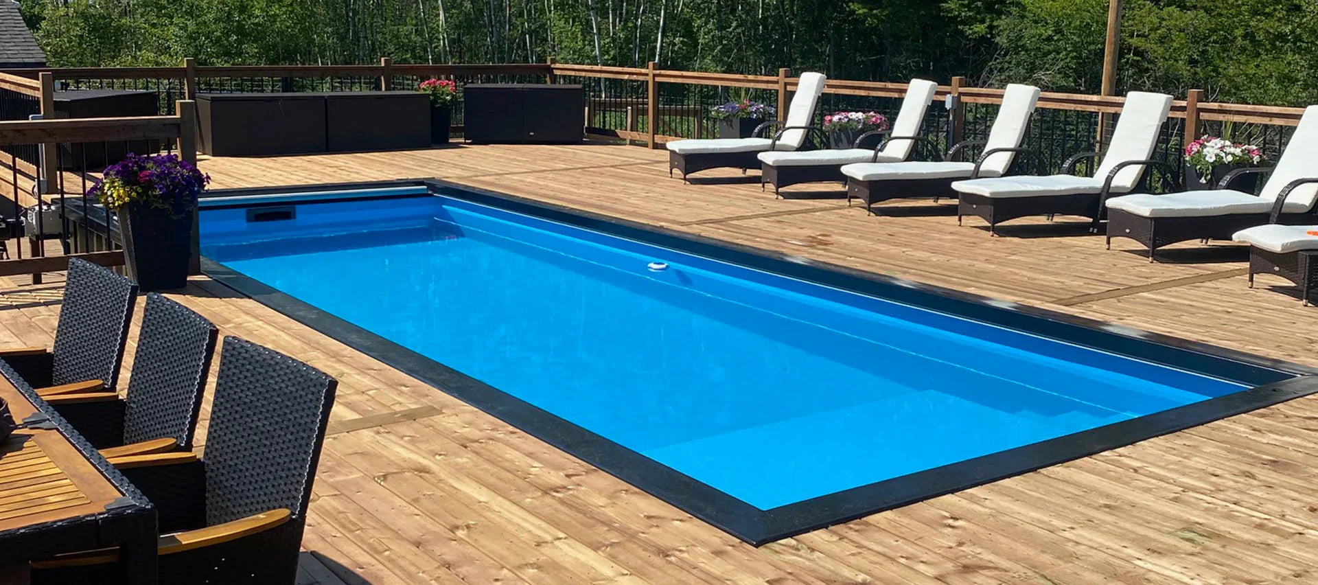 Piscine creusée moderne entourée de terrasse en bois, chaises longues et végétation extérieure