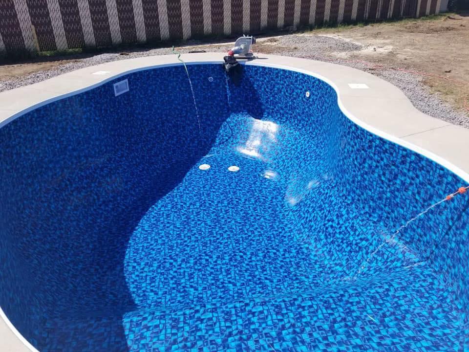 Piscine creusée en construction avec liner bleu mosaïque installée dans un jardin