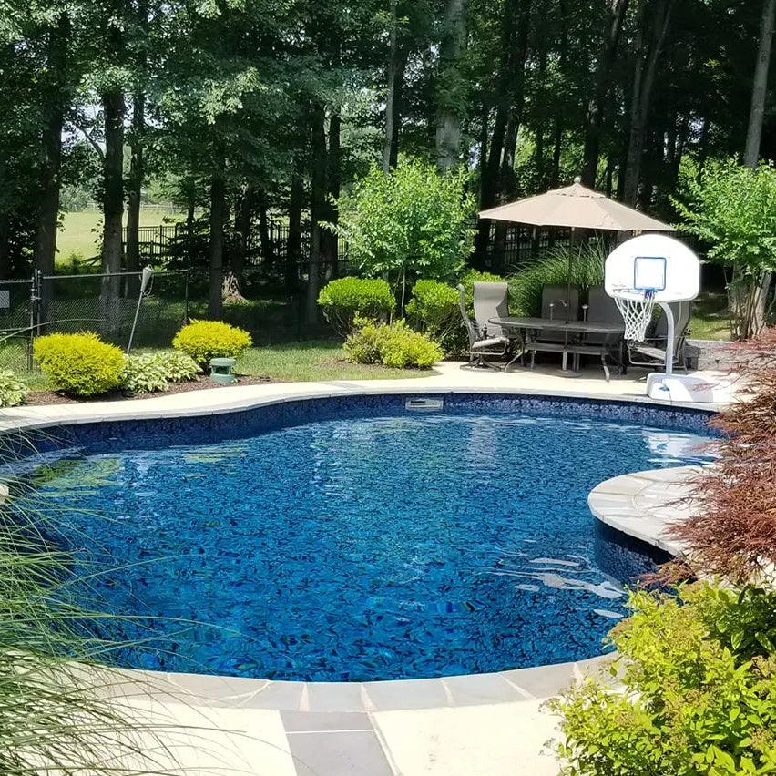 Piscine creusée extérieure avec margelle, eau bleue, coin détente et panneau de basket