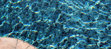 Reflets d’eau claire dans une piscine extérieure avec margelle en pierre visible