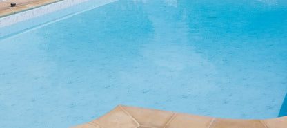 Margelle de piscine en pierre naturelle et eau bleue claire, revêtement Calacatta