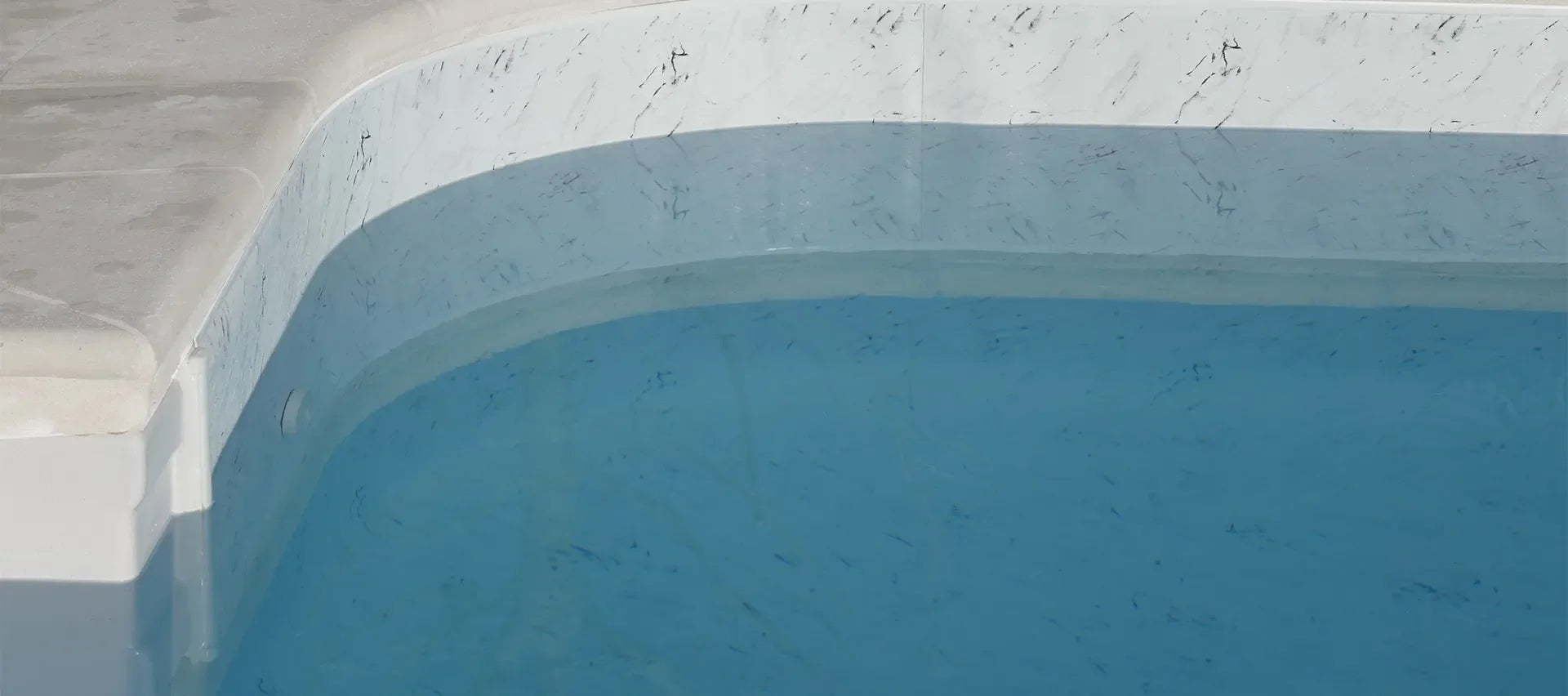 Angle de piscine avec revêtement effet marbre Calacatta et eau claire, design moderne