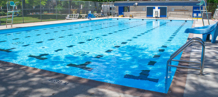 Piscine extérieure publique avec lignes de nage, toboggan, échelle et chaises de surveillance