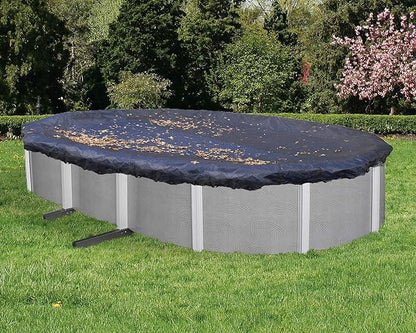 Piscine hors-sol ovale avec bâche de protection noire, feuilles sur la couverture, jardin verdoyant