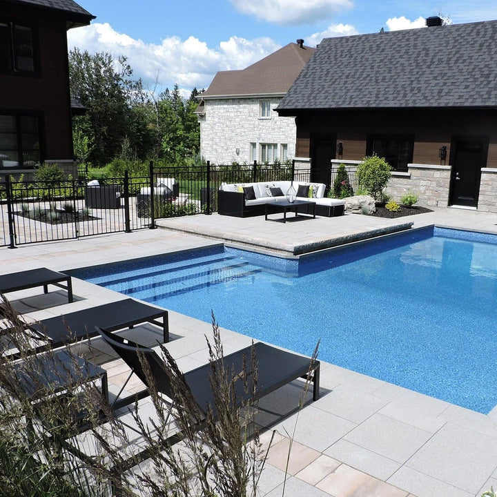 Piscine creusée moderne avec terrasse, chaises longues et salon extérieur, jardin résidentiel