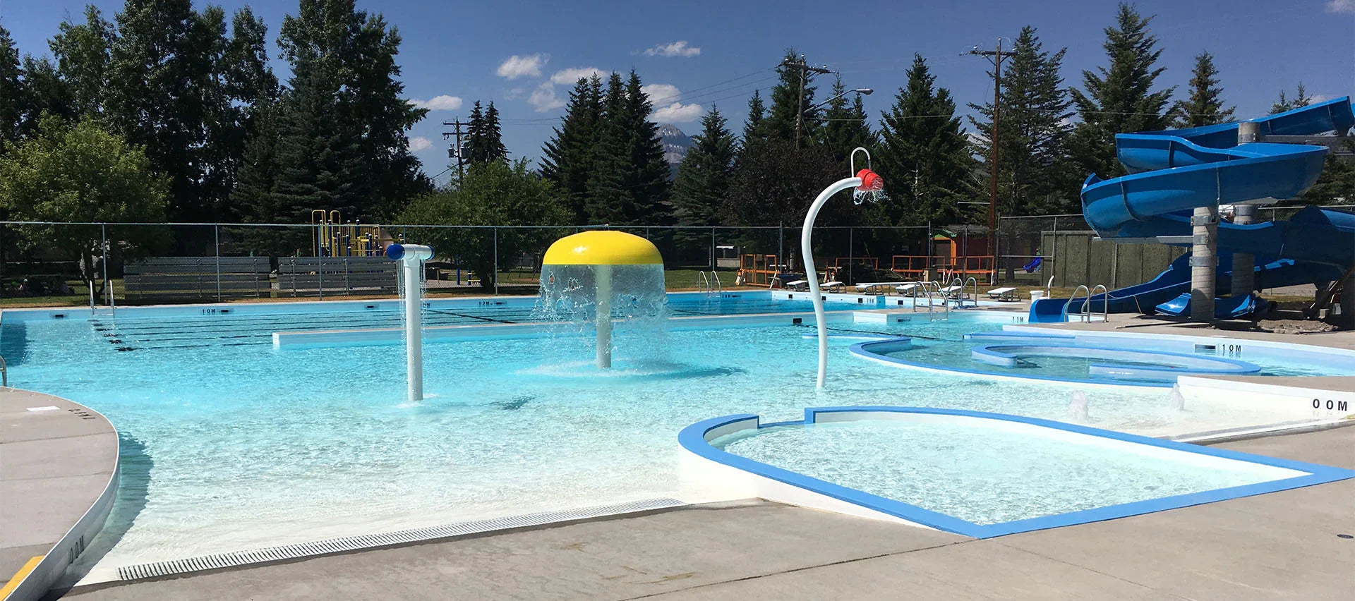 Piscine extérieure publique avec jeux d'eau, toboggan bleu et espace pataugeoire