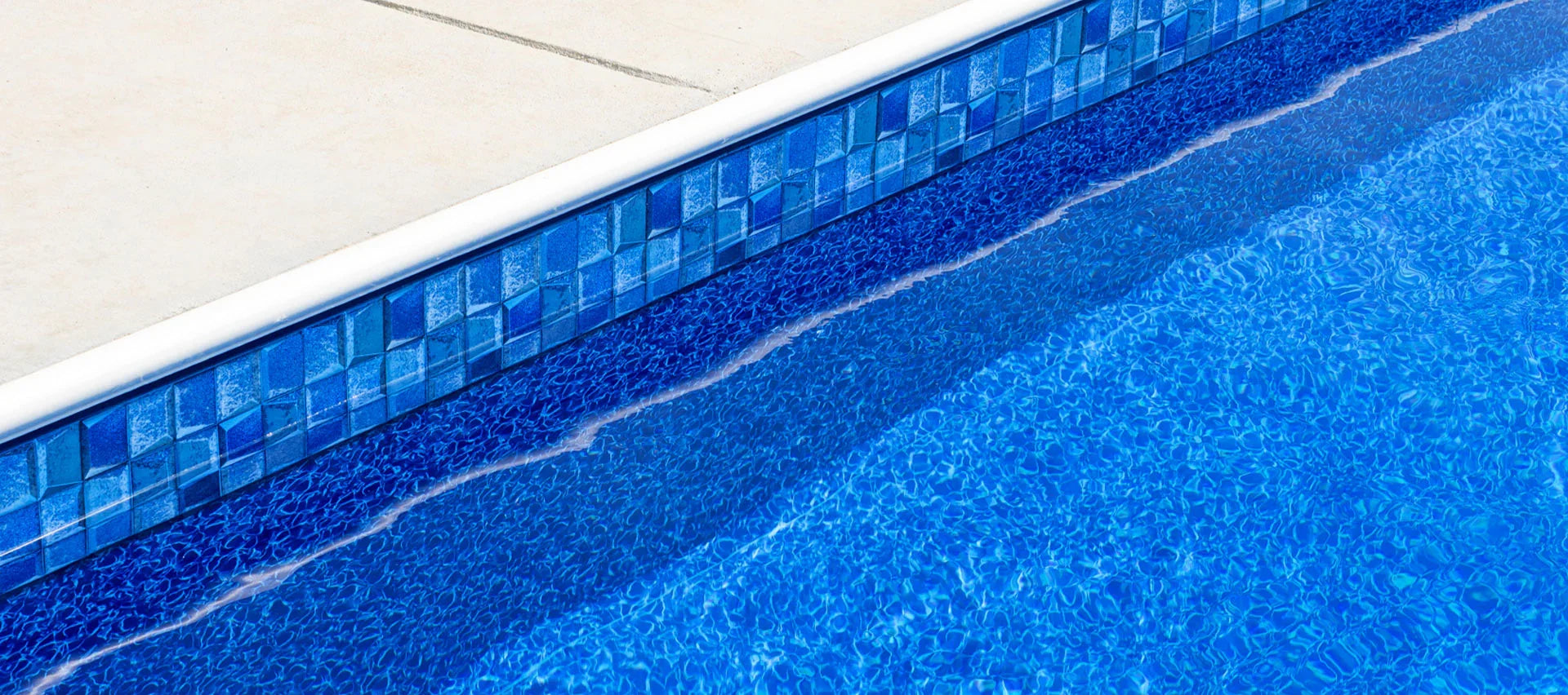 Margelle de piscine avec revêtement mosaïque bleu et eau claire ensoleillée