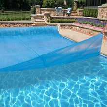 Couverture solaire bleue sur piscine extérieure, terrasse en pierre, jardin paysager