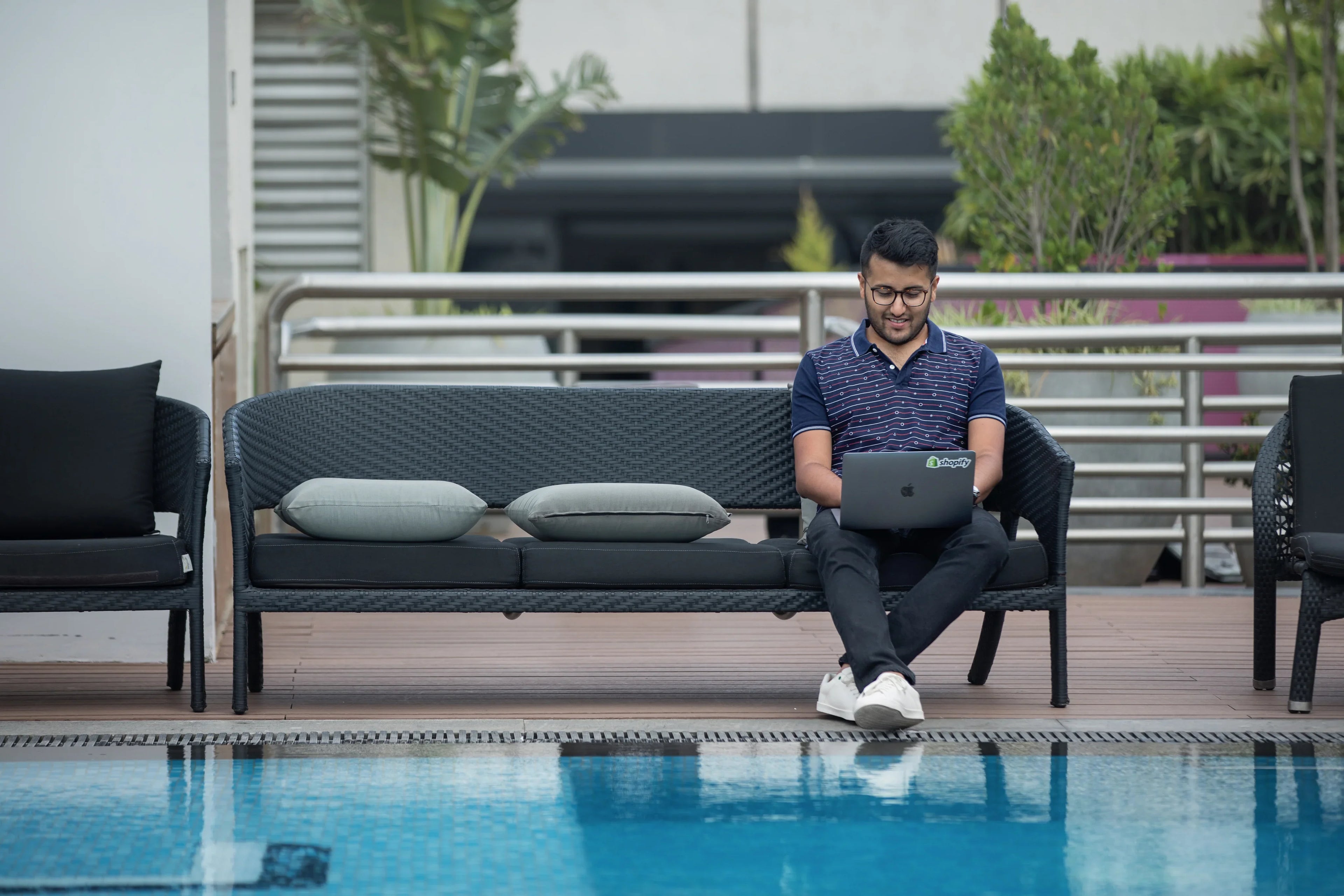 Homme travaillant sur un ordinateur portable près d'une piscine moderne en extérieur